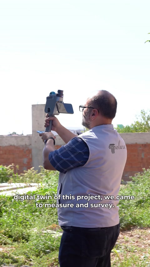 Tehnicianul orientează scanerul portabil spre partea superioară a clădirii.