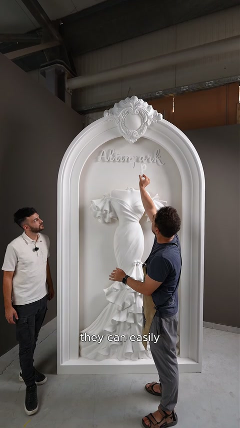 Cei doi meșteri explică reasamblarea inscripției deasupra rochiei sculptate.
