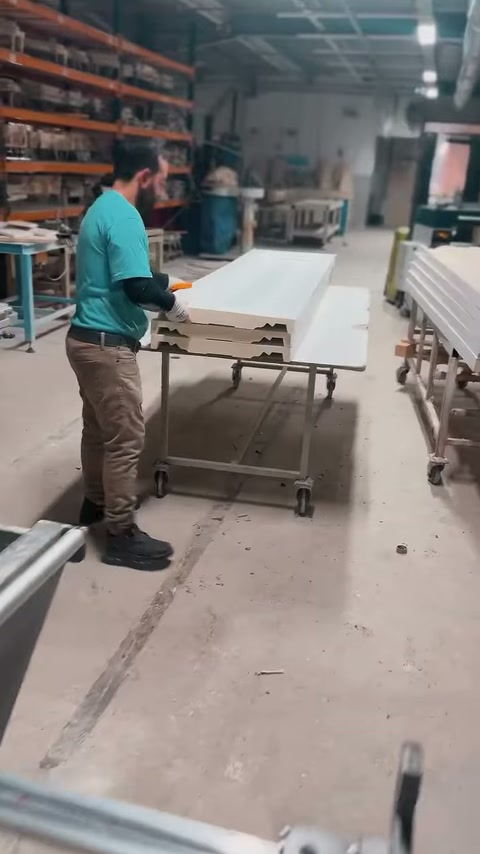 Muncitorul pregătește două elemente albe suprapuse pe un cărucior.