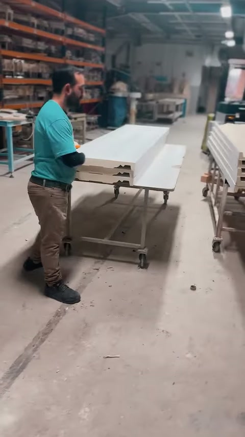 Operatorul examinează capetele profilate ale pieselor depozitate pe suporturi.