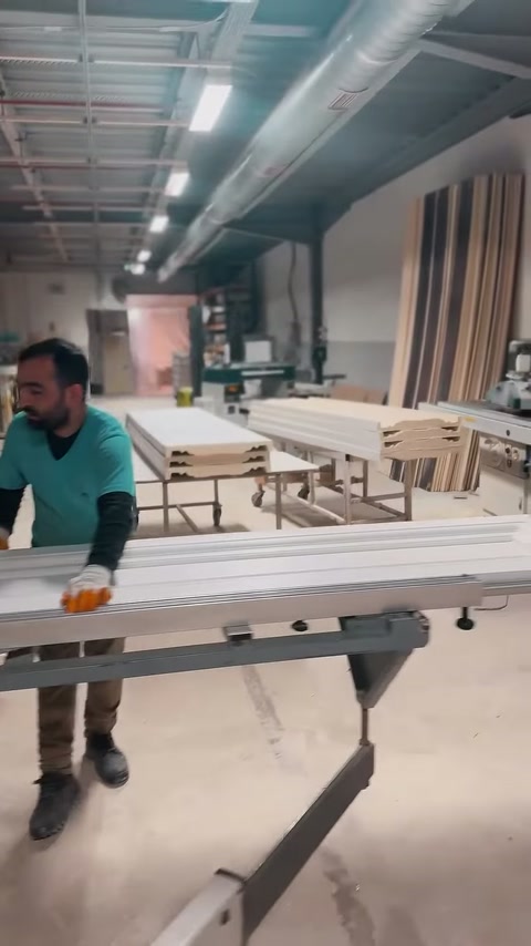 Operatorul conduce piesa profilată prin mașina din hala de producție.