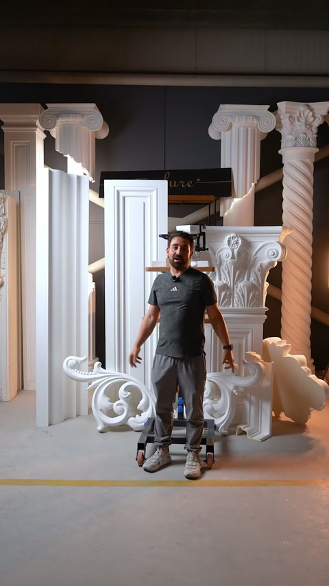 Prezentatorul stă în atelier între ornamentele portalului neasamblat