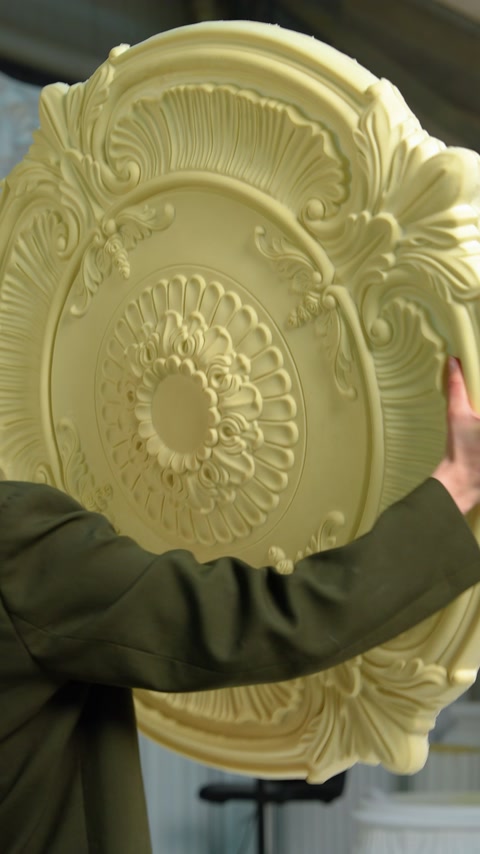 Persoană ține o rozetă texturată, culoare bej-verzuie, în atelier