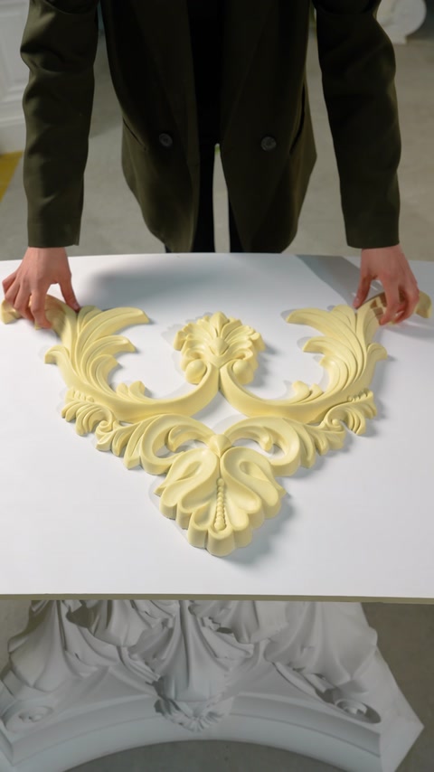 Mâini așază un ornament decorativ sculptat pe o masă albă