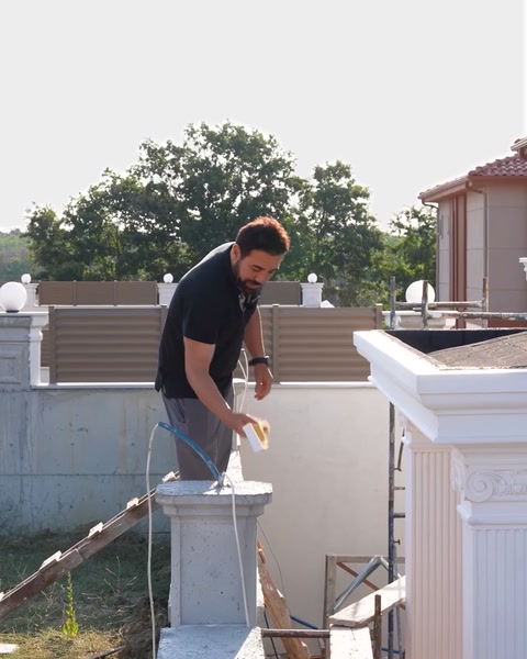 Aplicarea finisajului pe capitelul unei coloane ornamentale, pe schelă