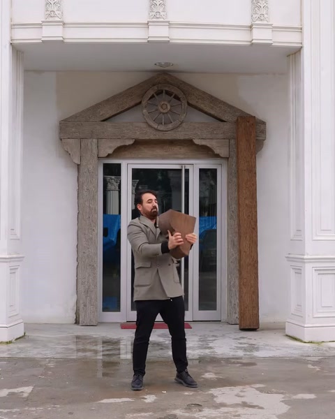 Bărbat ține panou decorativ din lemn lângă coloana intrării