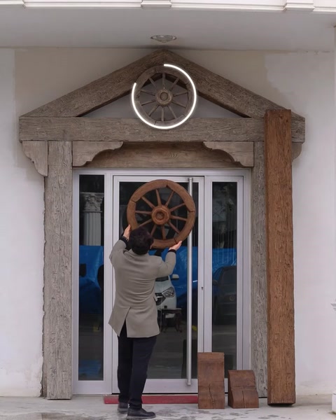Muncitor montează roată decorativă deasupra ușii de intrare