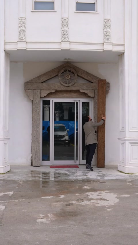 Intrarea este încadrată complet cu grinzi rustice și ornament circular.