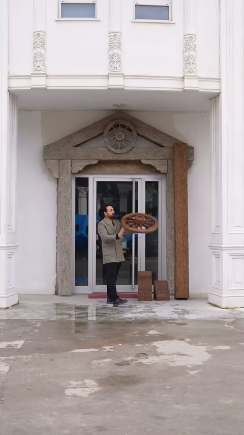 Prezentatorul rotește piesa circulară în fața ancadramentului decorativ.