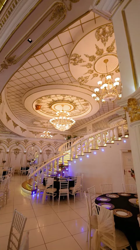 Scara curbată completează sala luxoasă cu rozete și candelabre ample.