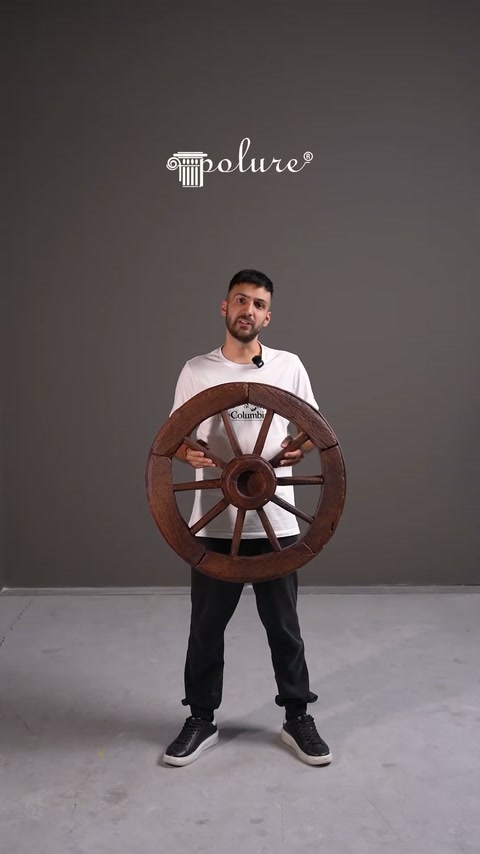 Roata ornamentală cu spițe este ținută vertical pentru prezentare.