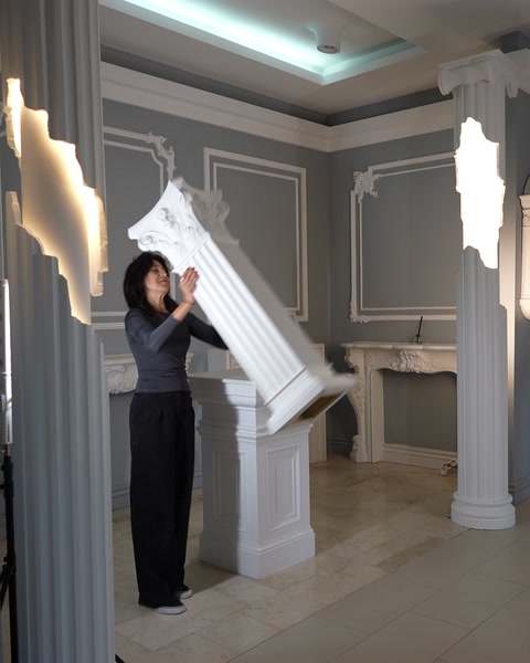 O femeie instalează o coloană decorativă într-un salon.