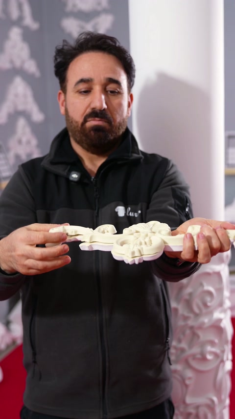 Meșterul susține ornamentul flexibil orizontal, pregătind demonstrația de curbare.