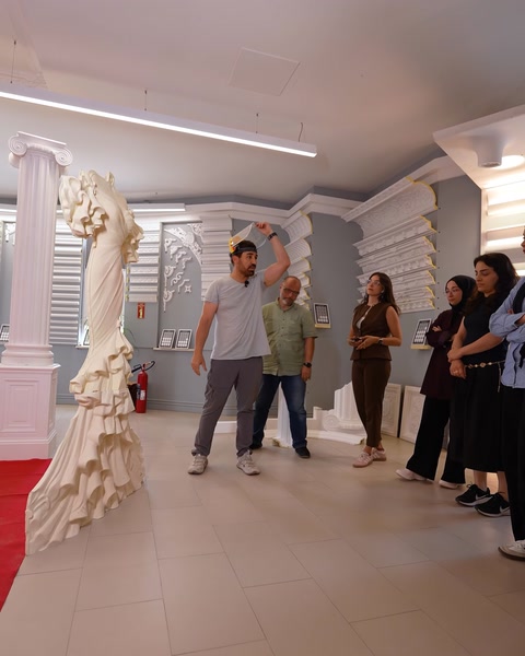 Grup de vizitatori lângă relief sculptural în formă de rochie de mireasă