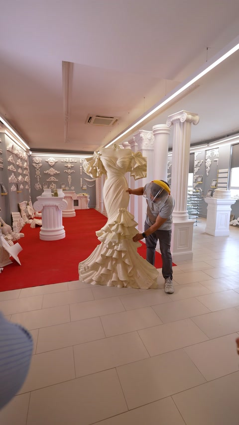 Muncitor cu cască ajustează relieful rochiei de mireasă pe suport