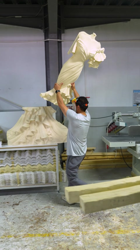 În atelier, un lucrător ridică o piesă sculptată pentru finisare