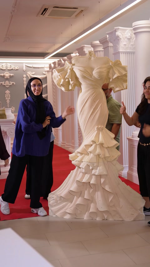 Femeie în ținută albastră trece prin showroom lângă coloane
