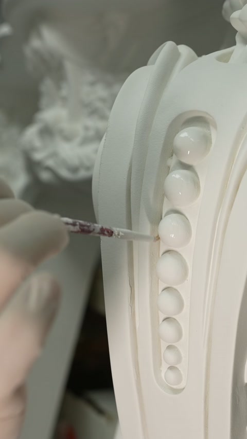 Meșterul finisează un ornament vertical cu motive circulare.